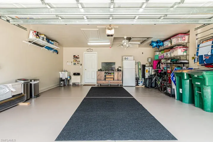 Garage featuring ceiling fan, white fridge, and a garage door opener