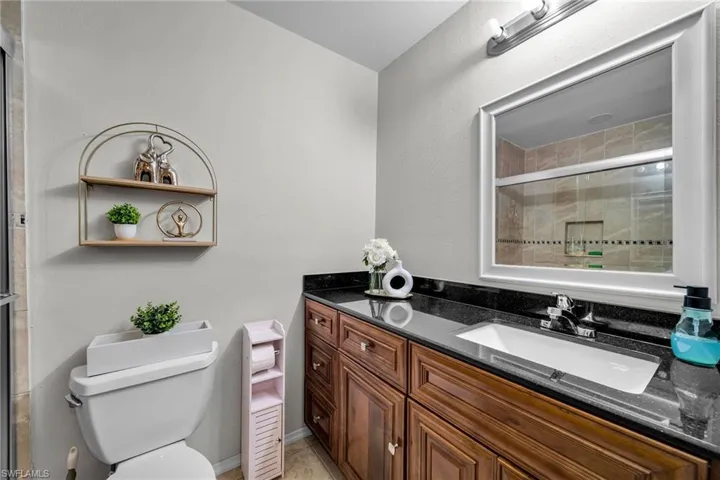 Bathroom featuring vanity, a shower with shower door, and toilet