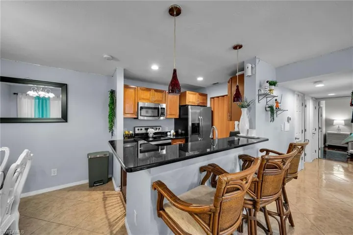 Kitchen with stainless steel appliances, hanging light fixtures, light tile patterned floors, and kitchen peninsula