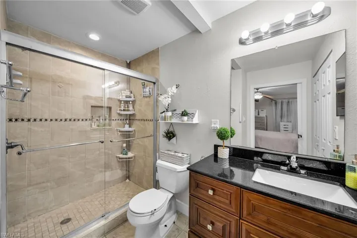 Bathroom with vanity, tile patterned flooring, toilet, and walk in shower