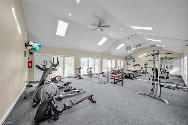 Workout area featuring high vaulted ceiling and ceiling fan