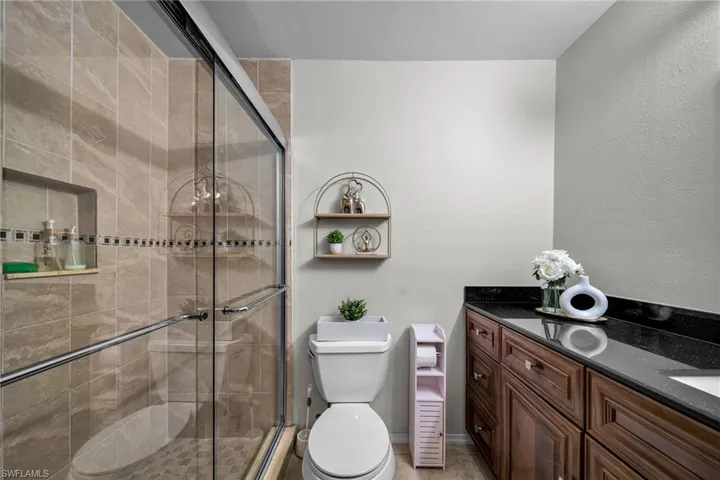 Bathroom featuring a shower with door, vanity, and toilet