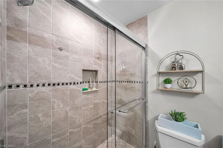 Bathroom featuring a shower with shower door and toilet