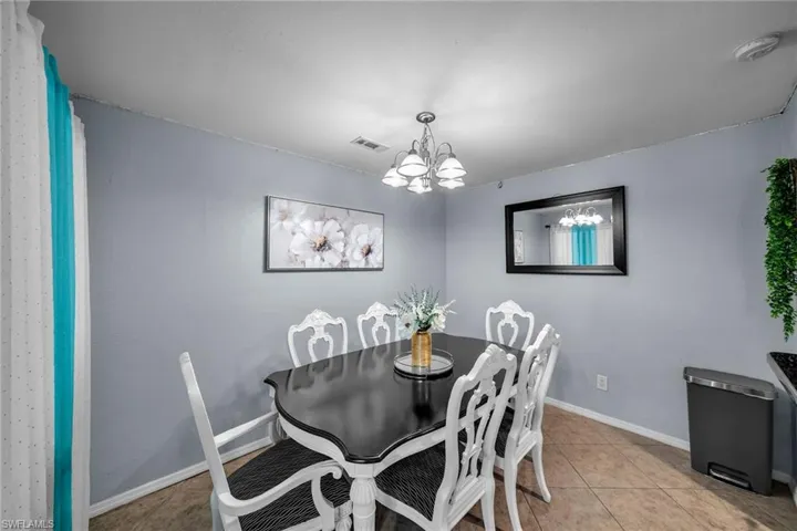 Dining space with light tile patterned floors and a notable chandelier