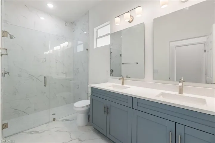 Bathroom with toilet, a shower with door, and vanity