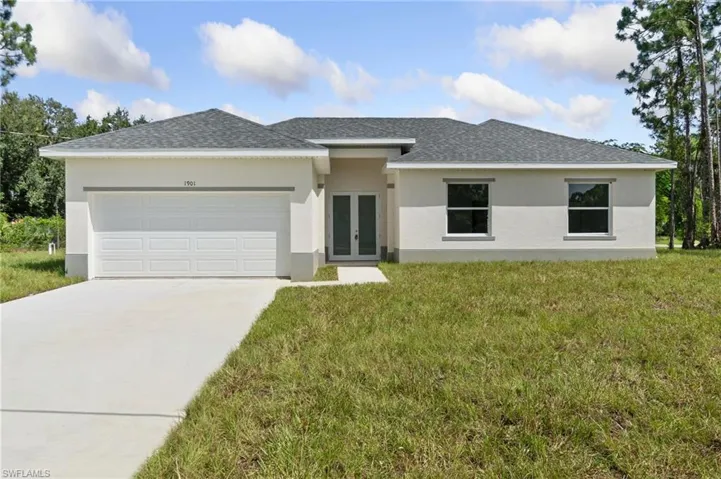 View of front of property with a garage and a front lawn