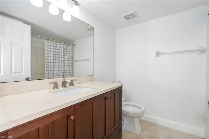 Full bath featuring a shower with shower curtain, vanity, and light tile patterned floors