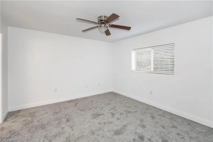 Carpeted empty room with baseboards and a ceiling fan