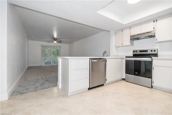 Kitchen featuring stainless steel appliances, white cabinets, light countertops, and a peninsula