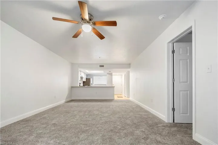 Unfurnished living room featuring ceiling fan and light colored carpet