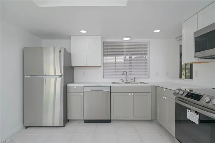 Kitchen with sink, light tile patterned floors, appliances with stainless steel finishes, and gray cabinets