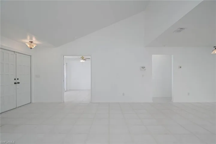 Empty room featuring high vaulted ceiling, ceiling fan, and light tile patterned floors