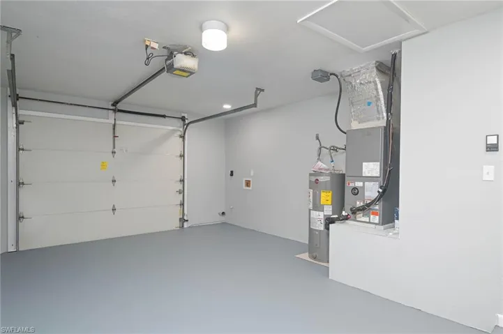 Garage featuring electric water heater and a garage door opener