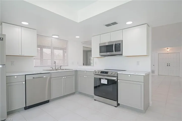 Kitchen featuring gray cabinetry, light tile patterned floors, and appliances with stainless steel finishes