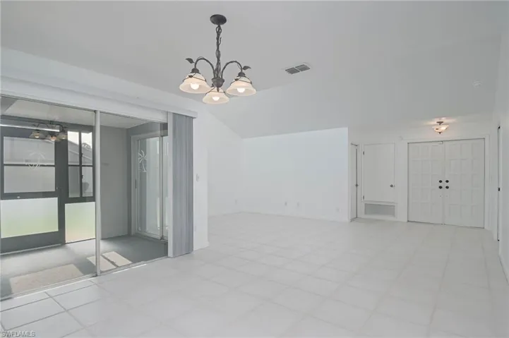 Spare room featuring a notable chandelier and light tile patterned flooring