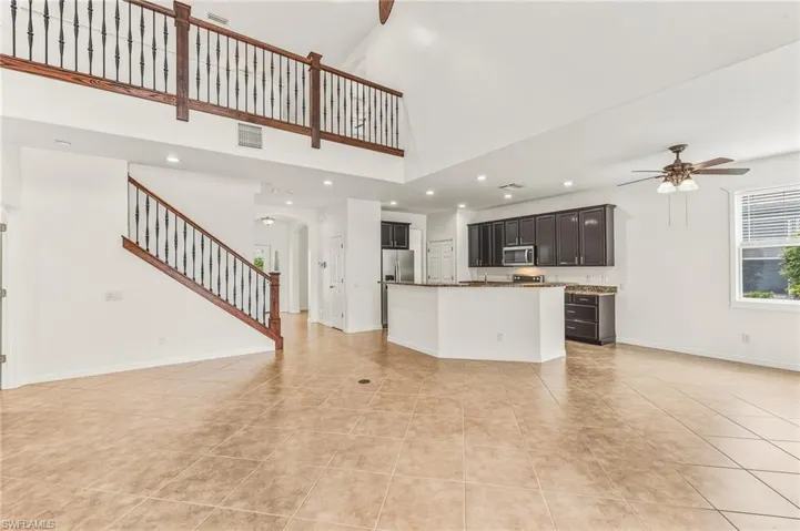 Kitchen with open floor plan, arched walkways, an island with sink, recessed lighting, and a ceiling fan