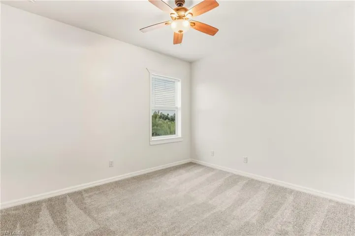 Empty room featuring carpet floors and a ceiling fan