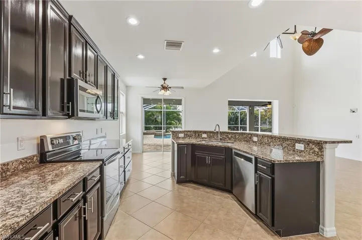 Kitchen with stainless steel appliances, ceiling fan, dark brown cabinets, recessed lighting, and light tile patterned floors