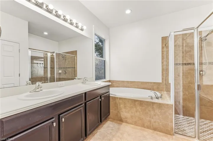 Full bathroom with double vanity, a bath, a stall shower, light tile patterned floors, and recessed lighting
