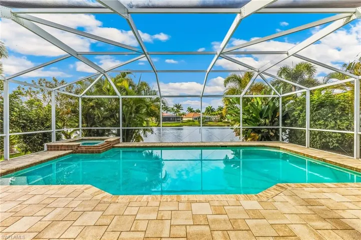 View of pool with a sunroom, a water view, a lanai, a pool with connected hot tub, and a patio