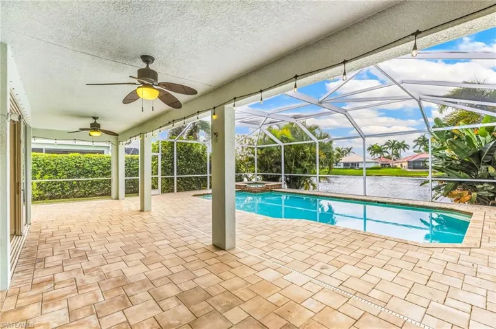 View of pool featuring a patio, a sunroom, a pool with connected hot tub, and glass enclosure