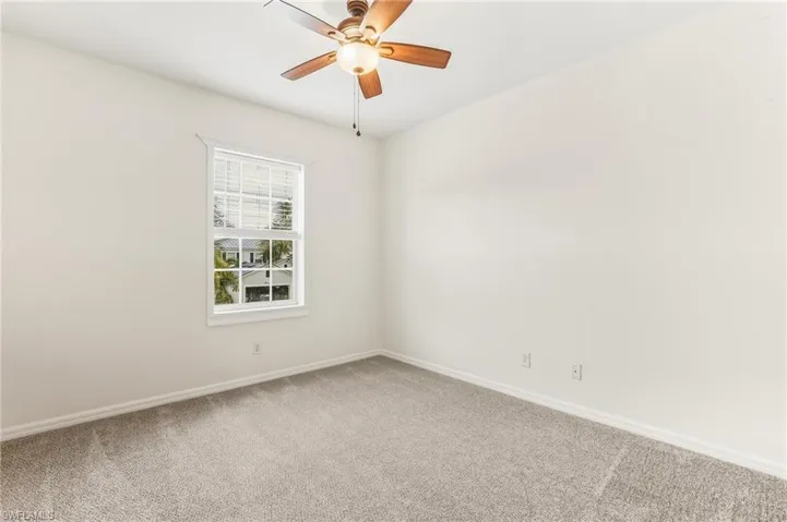 Carpeted empty room featuring ceiling fan and baseboards
