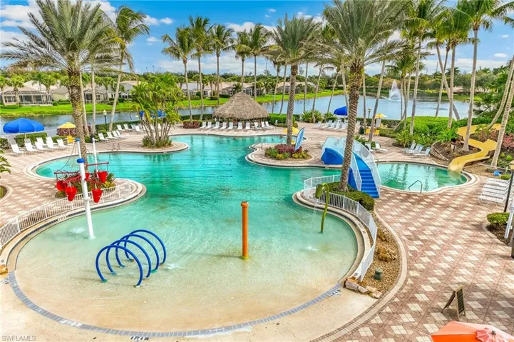 Community pool featuring a water play area, a water slide, a water view, and a patio