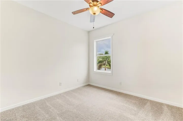 Carpeted spare room featuring baseboards and ceiling fan