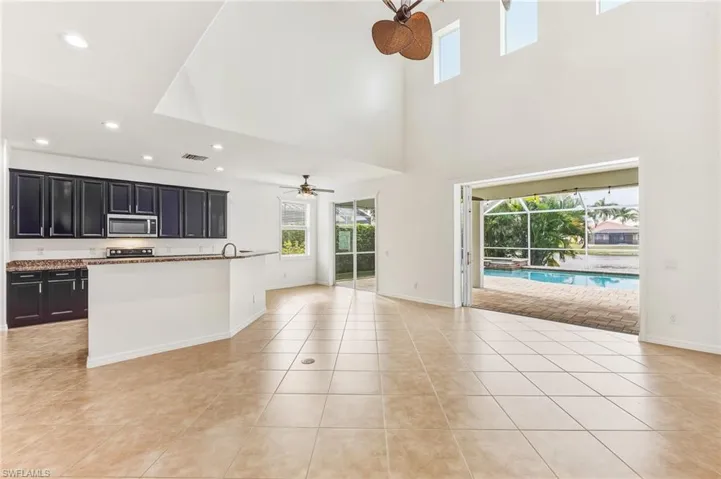 Kitchen featuring dark cabinets, stainless steel appliances, open floor plan, ceiling fan, and recessed lighting