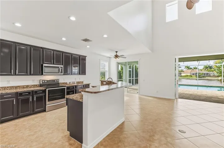 Kitchen with stainless steel appliances, recessed lighting, light tile patterned floors, light stone counters, and ceiling fan