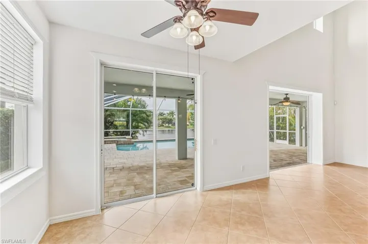 Unfurnished room featuring a sunroom, light tile patterned floors, ceiling fan, and high vaulted ceiling
