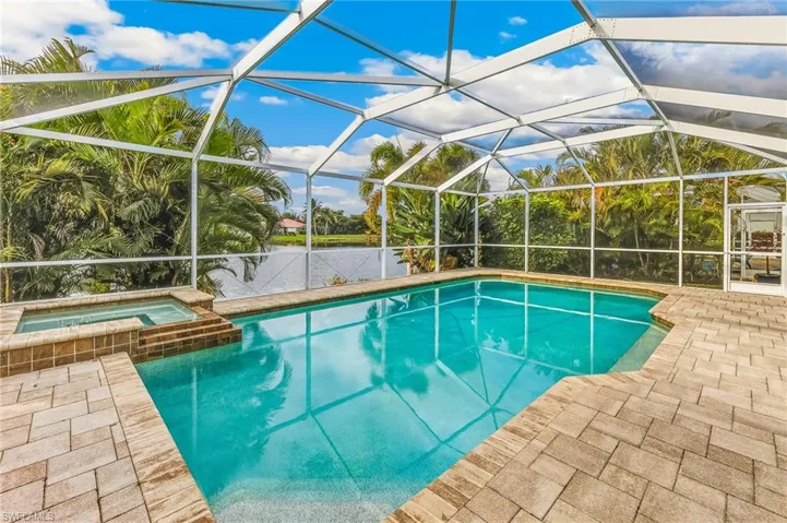 View of swimming pool featuring a pool with connected hot tub, a sunroom, a patio, a water view, and a lanai