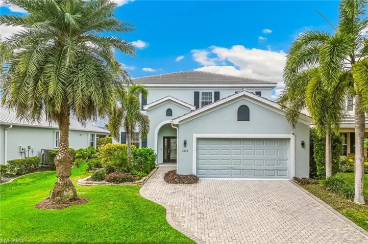 View of front of home featuring stucco siding, decorative driveway, a front lawn, and an attached garage