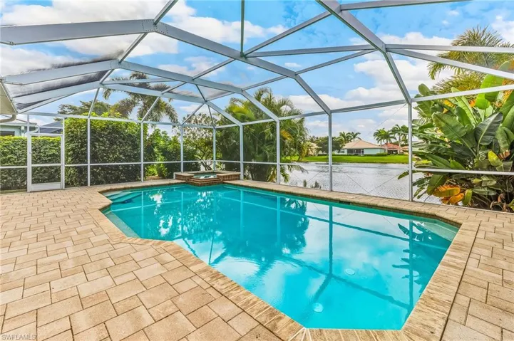 View of swimming pool featuring a water view, a pool with connected hot tub, a lanai, a sunroom, and a patio