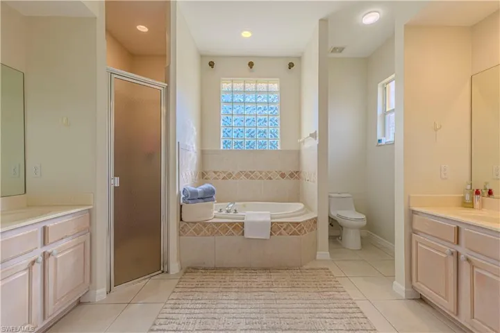 Full bathroom with tile patterned flooring, vanity, separate shower and tub, and toilet