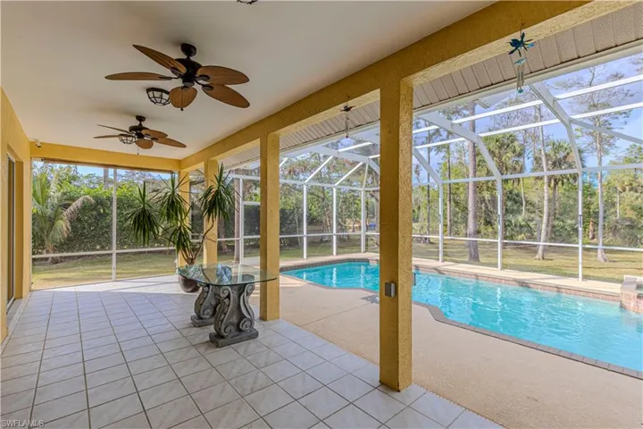 View of pool with a lanai, a patio area, and ceiling fan