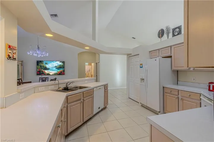 Kitchen featuring light brown cabinetry, white appliances, and sink