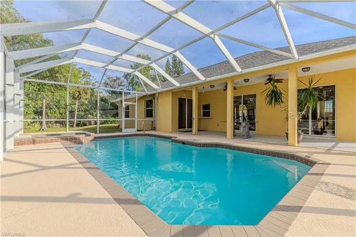 View of swimming pool with an in ground hot tub, a patio, ceiling fan, and a lanai