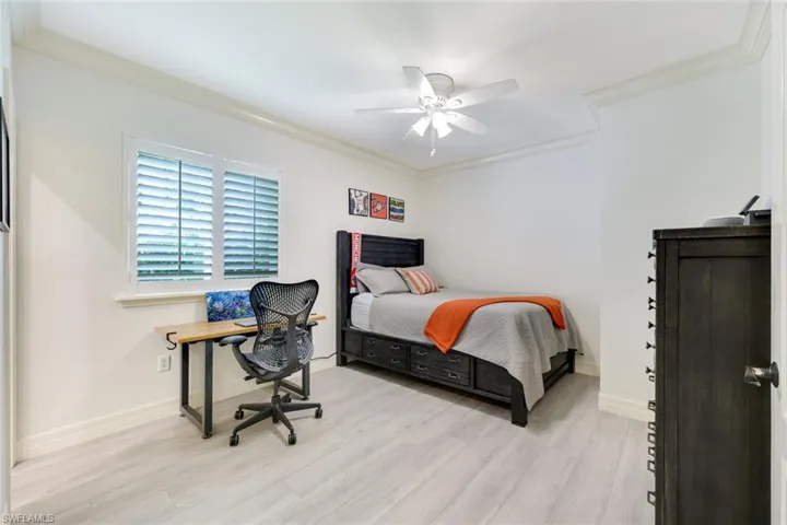 Bedroom with crown molding, light wood finished floors and a ceiling fan.