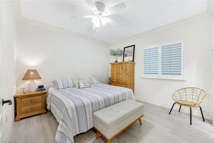 Bedroom with crown molding, wood finished floors, and a ceiling fan