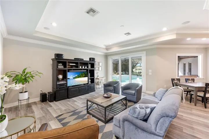 Comfortable family room with crown molding, impact glass sliders, and tray ceilings