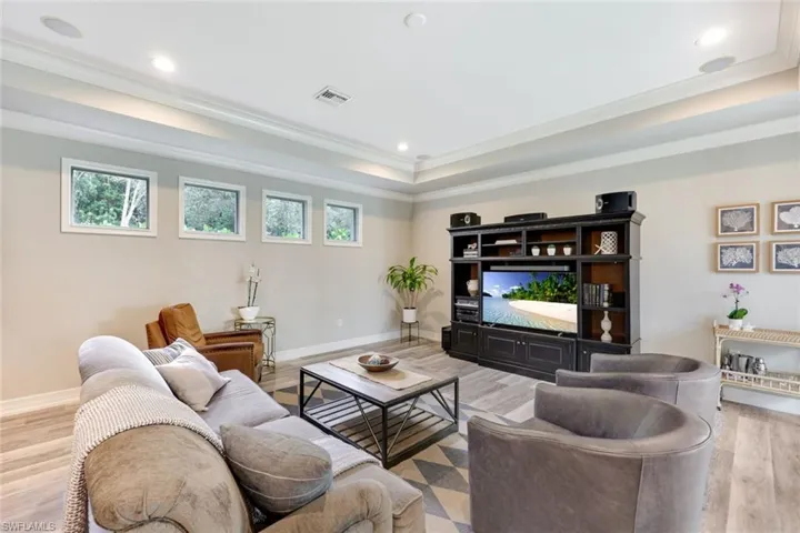 Spacious family room featuring elegant tray ceilings, offering a delightful view of the inviting pool area.