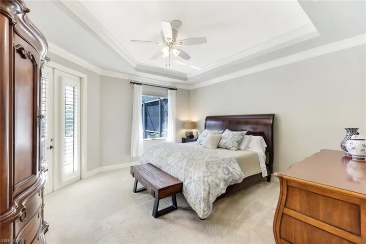 Spacious Primary Bedroom featuring elegant crown molding and a luxurious tray ceiling, complemented by plush, comfortable carpeted flooring.