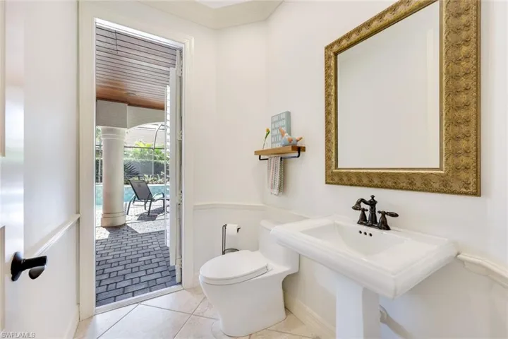 Bathroom in a charming half cabana structure, featuring light-colored tile flooring and decorative molding.