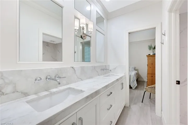 Full bath with crown molding, tasteful backsplash, double vanity, ensuite bathroom, and light wood-type flooring