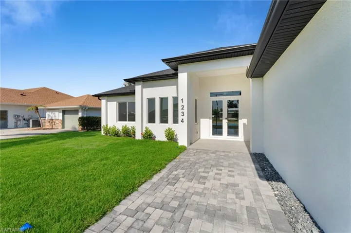 Entrance to property with french doors, stucco siding, and a yard