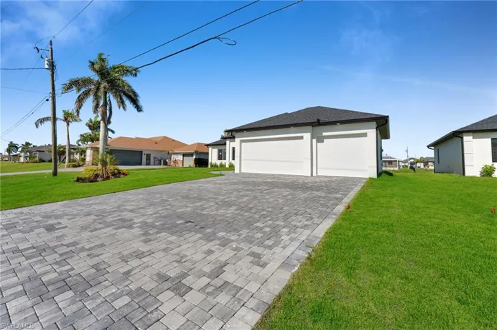 View of front of property with decorative driveway, a garage, a residential view, and a front lawn