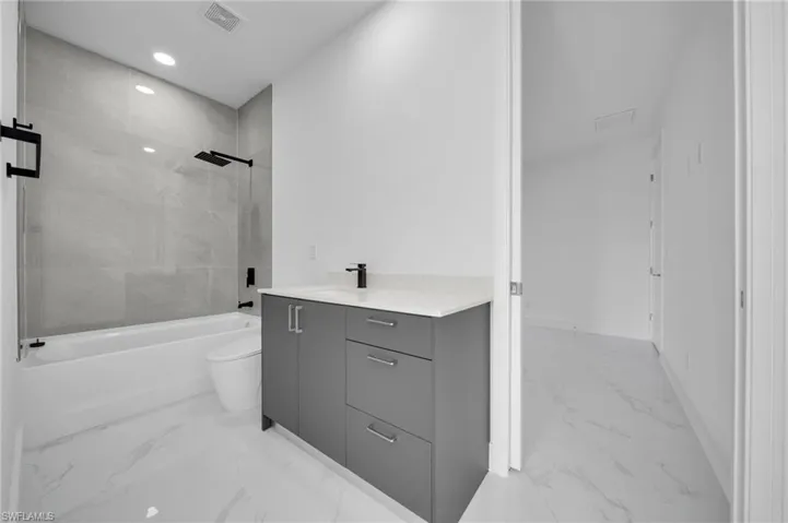 Full bathroom with visible vents, shower / washtub combination, vanity, toilet, and marble finish floor