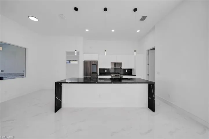 Kitchen with marble finish floor, dark countertops, modern cabinets, white cabinetry, and appliances with stainless steel finishes