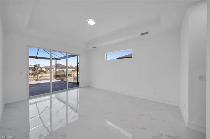 Empty room with visible vents, marble finish floor, baseboards, a sunroom, and a tray ceiling